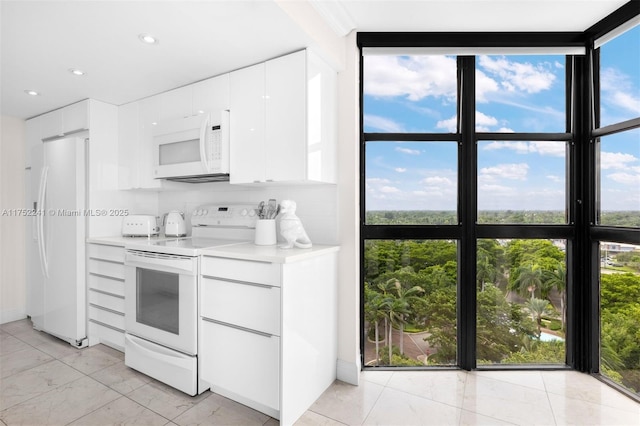 kitchen with light countertops, expansive windows, white cabinets, modern cabinets, and white appliances