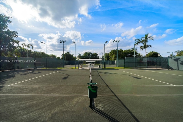 view of tennis court featuring community basketball court and fence