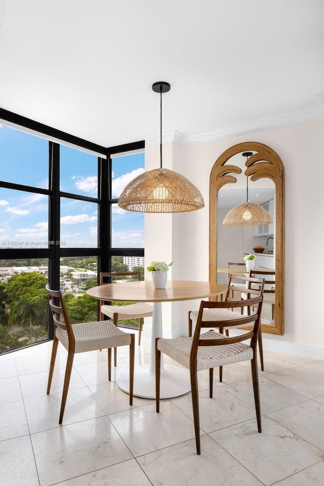 dining area featuring baseboards, ornamental molding, and a wall of windows