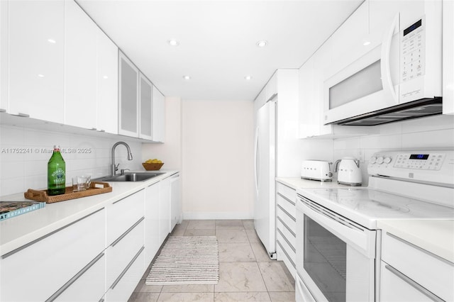 kitchen with white appliances, a sink, white cabinets, light countertops, and modern cabinets