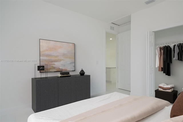 bedroom with light tile patterned floors, a closet, visible vents, and attic access