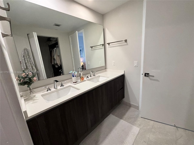 full bathroom featuring a walk in closet, visible vents, a sink, and double vanity