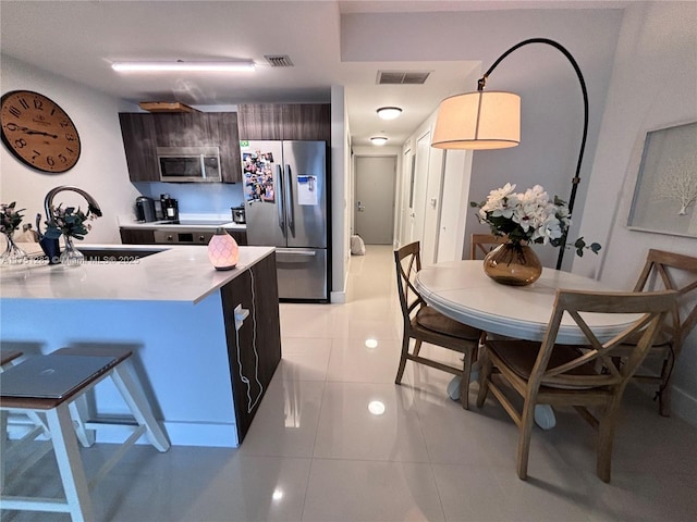 kitchen with light countertops, visible vents, appliances with stainless steel finishes, a sink, and dark brown cabinets