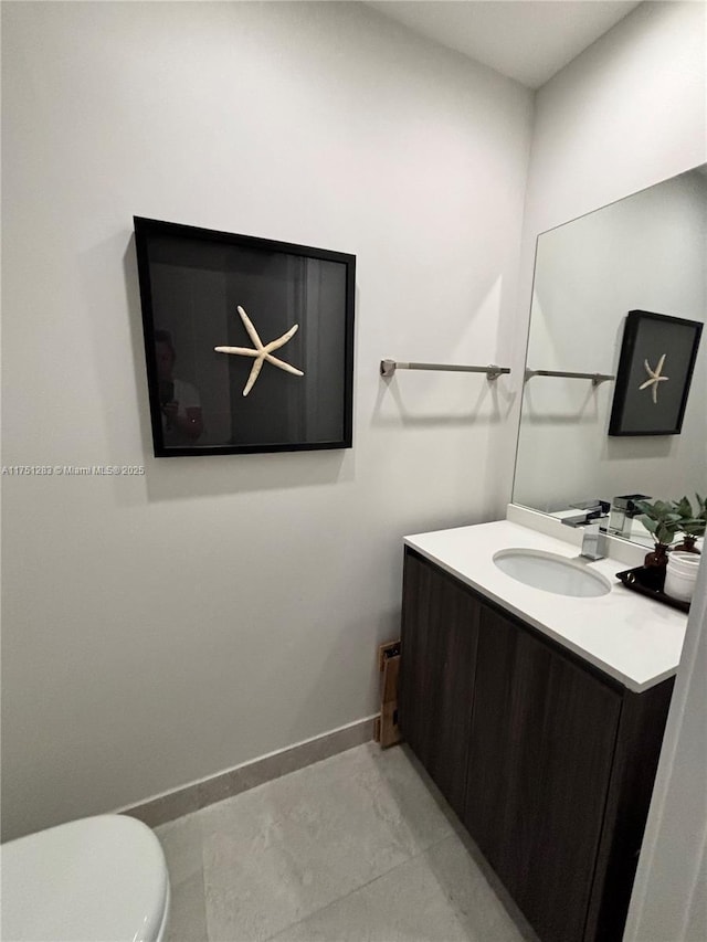 bathroom featuring toilet, vanity, and baseboards