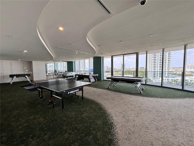 recreation room featuring floor to ceiling windows, carpet flooring, visible vents, and a city view