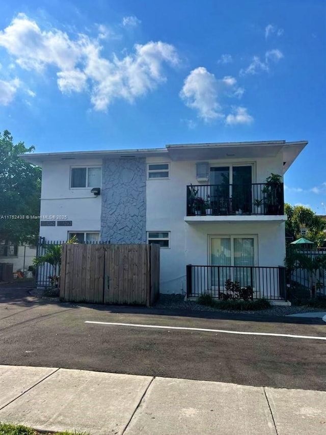 exterior space with fence, a balcony, and stucco siding