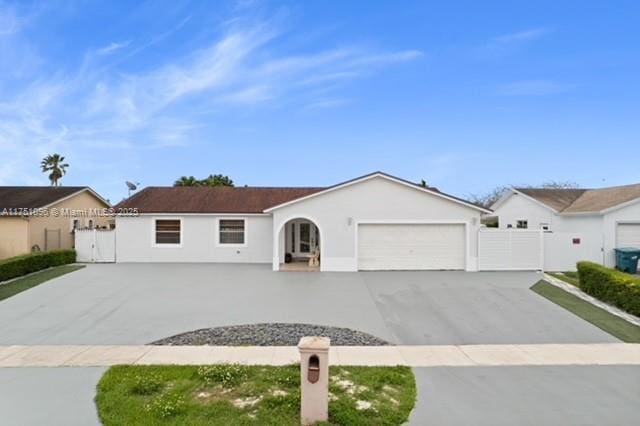 single story home with an attached garage, fence, stucco siding, a gate, and driveway