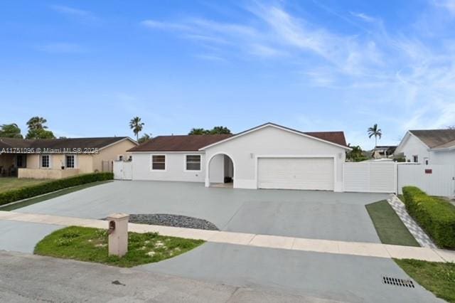 ranch-style house with an attached garage, fence, a gate, and driveway