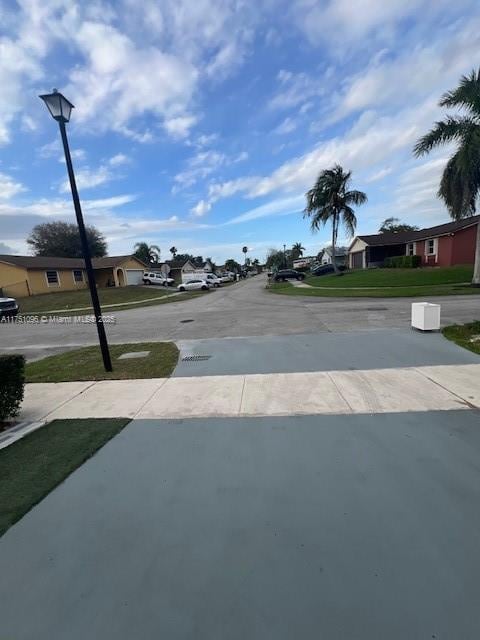 view of road with a residential view, sidewalks, and street lights