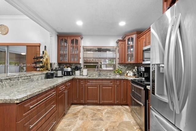 kitchen with stainless steel appliances, light stone countertops, glass insert cabinets, and a sink