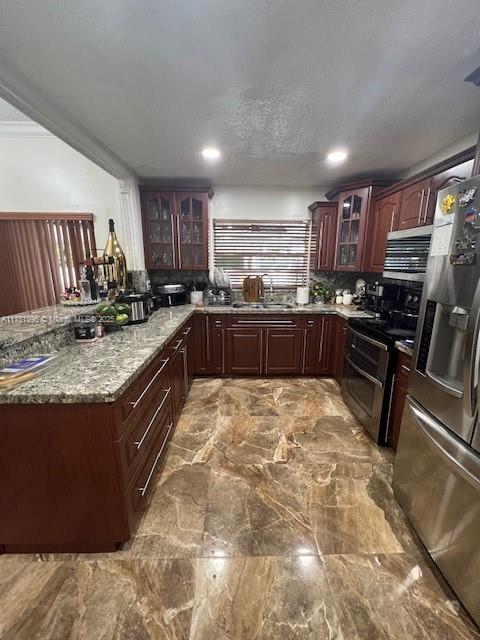 kitchen featuring glass insert cabinets, stone countertops, appliances with stainless steel finishes, and a sink