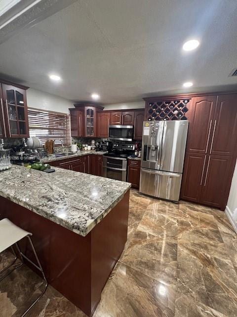 kitchen featuring a peninsula, marble finish floor, glass insert cabinets, and stainless steel appliances