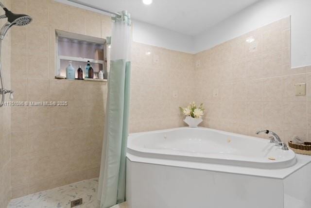 full bathroom with a bath, tile walls, and a stall shower