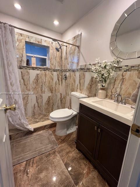 bathroom with marble finish floor, tile walls, toilet, a stall shower, and vanity