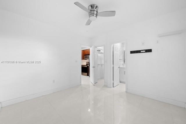 unfurnished room with ceiling fan and baseboards