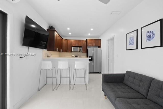 kitchen with a kitchen breakfast bar, a peninsula, appliances with stainless steel finishes, light countertops, and open floor plan