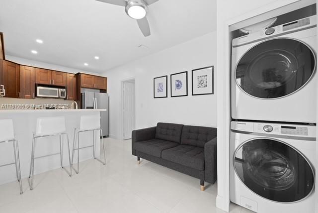 laundry room with ceiling fan, recessed lighting, stacked washer / dryer, and laundry area