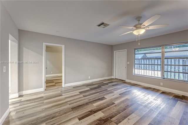 unfurnished room with light wood-style flooring, a ceiling fan, visible vents, and baseboards