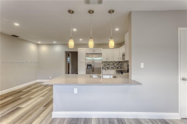 kitchen with decorative light fixtures, light countertops, appliances with stainless steel finishes, white cabinetry, and a sink