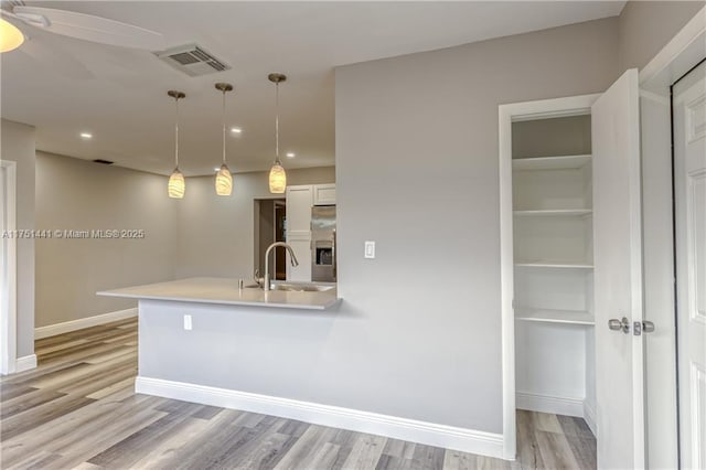 kitchen featuring decorative light fixtures, light countertops, visible vents, a sink, and stainless steel fridge