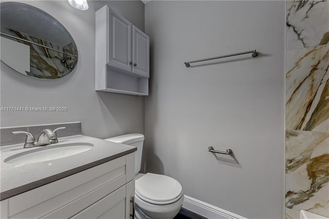 bathroom with toilet, baseboards, and vanity