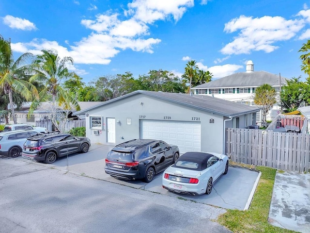 view of car parking featuring an attached garage, driveway, and fence