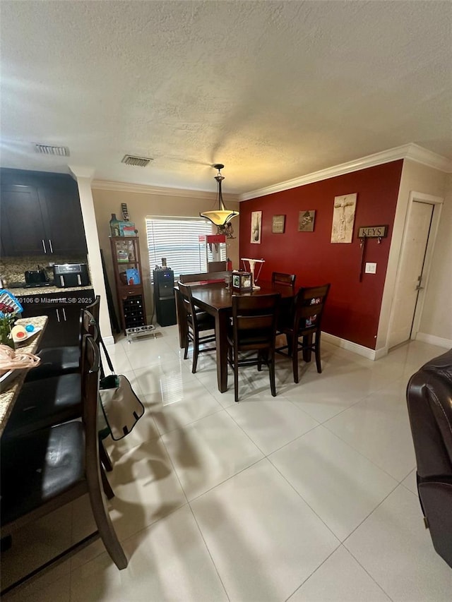 dining space featuring a textured ceiling, visible vents, and crown molding