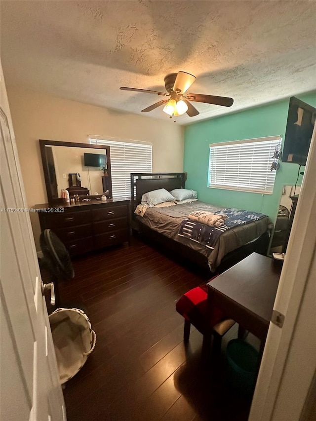 bedroom with dark wood-type flooring, a textured ceiling, and a ceiling fan