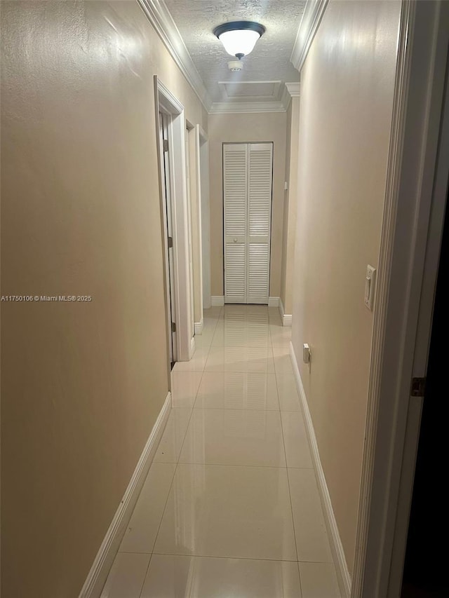 hall with light tile patterned floors, crown molding, baseboards, and a textured ceiling