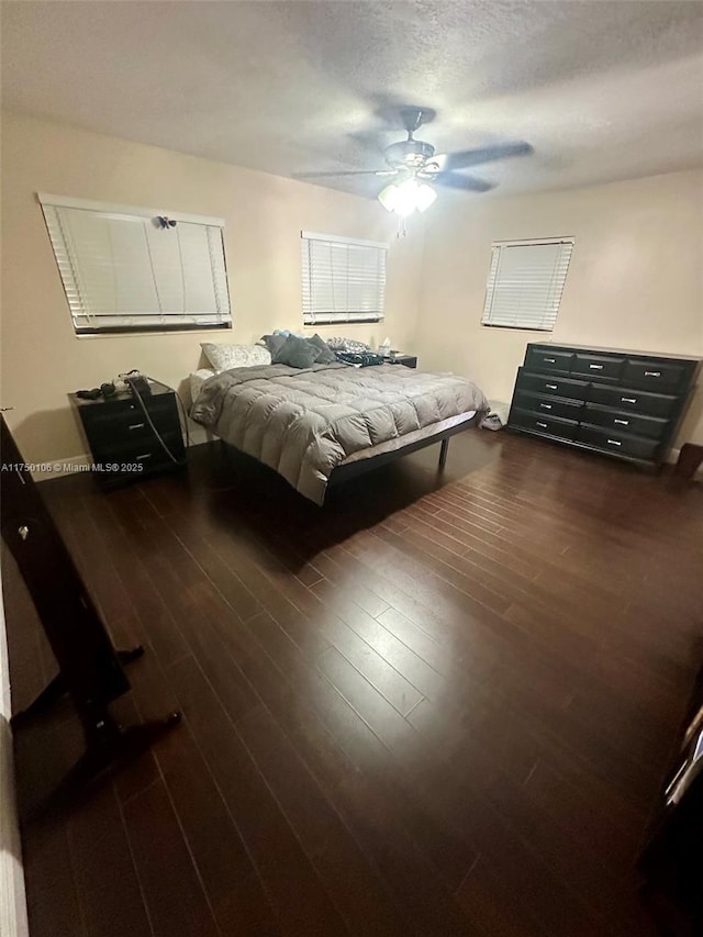 bedroom featuring dark wood-type flooring, ceiling fan, and a textured ceiling