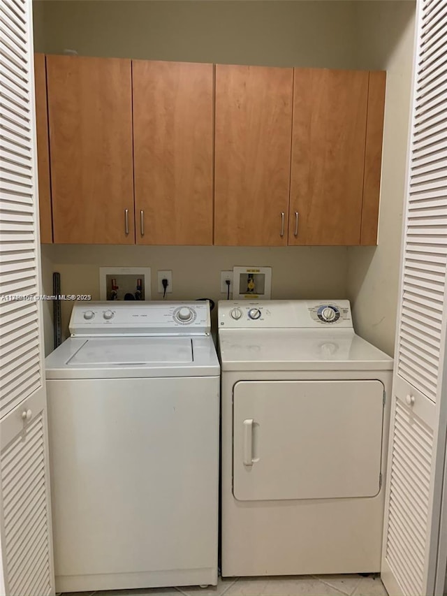 clothes washing area featuring washing machine and clothes dryer and cabinet space