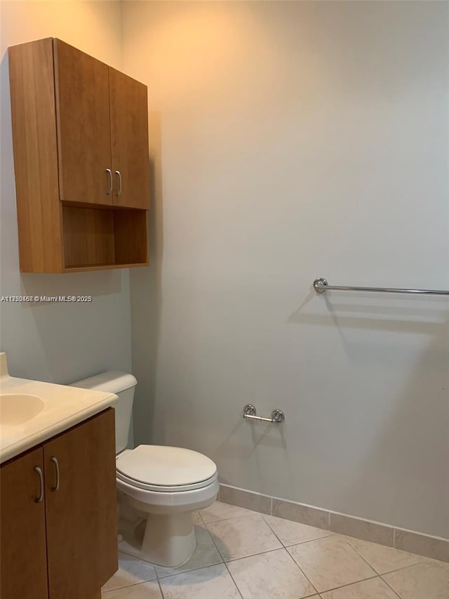 bathroom with tile patterned flooring, baseboards, vanity, and toilet