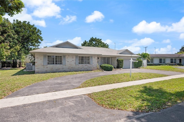 single story home with a garage, a front lawn, aphalt driveway, and brick siding