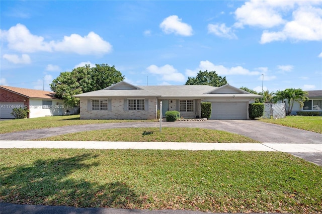 single story home featuring aphalt driveway, a front yard, brick siding, and a garage