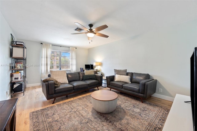 living room featuring light wood-style floors, visible vents, baseboards, and a ceiling fan