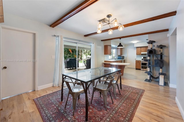 dining room featuring light wood finished floors, visible vents, baseboards, a chandelier, and beam ceiling