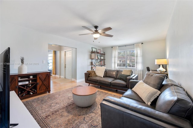 living room featuring a ceiling fan, baseboards, and wood finished floors