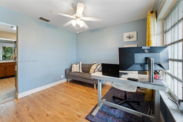 office area featuring a ceiling fan, visible vents, baseboards, and wood finished floors