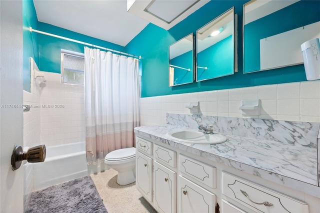 bathroom featuring toilet, vanity, tile walls, wainscoting, and shower / bathtub combination with curtain