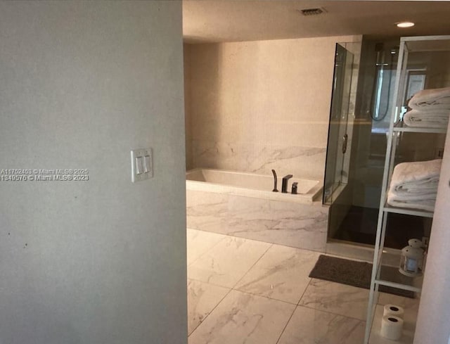 bathroom with marble finish floor, visible vents, and a bath