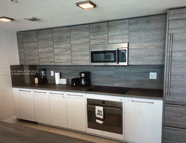 kitchen featuring black appliances, dark countertops, and decorative backsplash