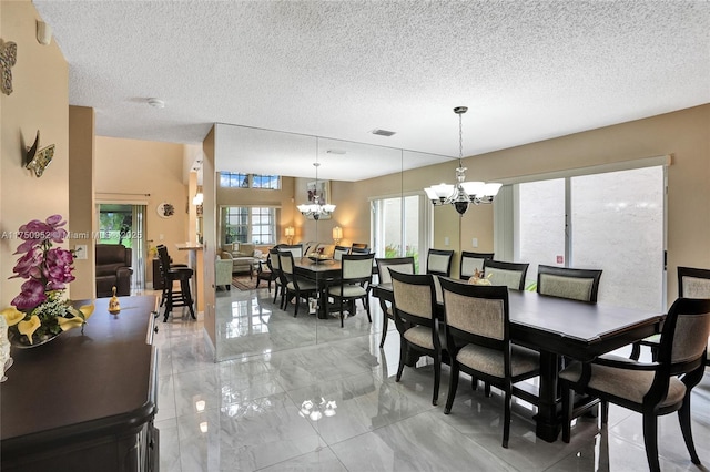 dining space featuring a textured ceiling, marble finish floor, visible vents, and an inviting chandelier