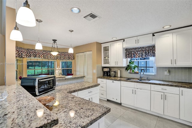 kitchen with a sink, white cabinetry, pendant lighting, and dishwasher