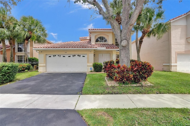 mediterranean / spanish home with aphalt driveway, a garage, a tiled roof, stucco siding, and a front yard