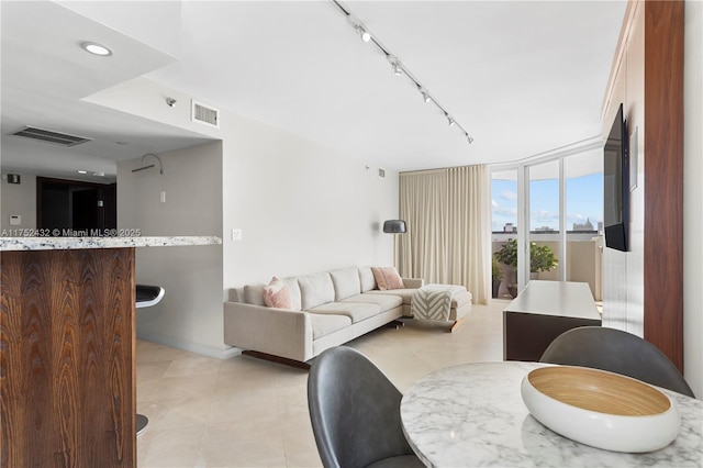 living room with rail lighting, expansive windows, visible vents, and light tile patterned flooring