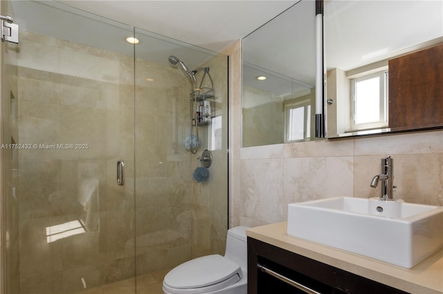 full bathroom featuring a stall shower, tile walls, vanity, and toilet