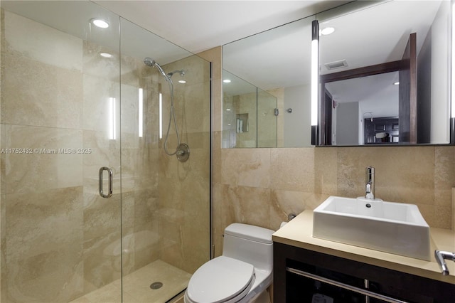 bathroom featuring tile walls, backsplash, toilet, a stall shower, and vanity