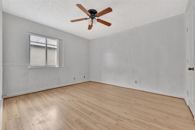 empty room with a textured ceiling, light wood-type flooring, a ceiling fan, and baseboards