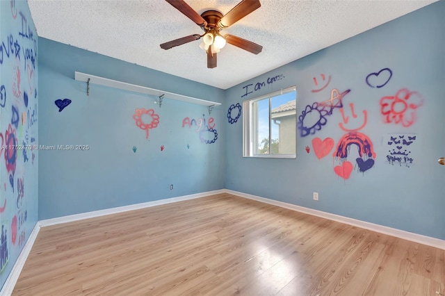 spare room with light wood-style floors, a textured ceiling, baseboards, and a ceiling fan