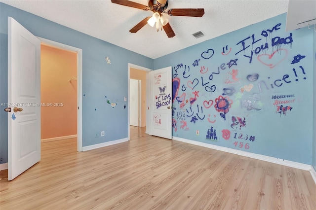 unfurnished bedroom featuring light wood finished floors, visible vents, and a textured ceiling